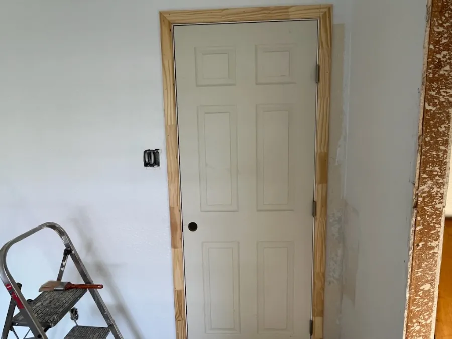 Interior door hung in new pine casing, walls patched and ready for paint