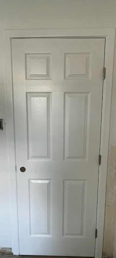 Interior six panel door with its casing and jamb finished in clean white paint