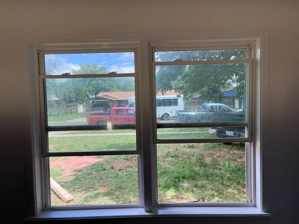 The same window after painting, with crisp white trim and sill against a warm repainted wall